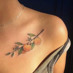 a woman's chest with an orange branch tattoo on her left shoulder and back