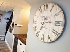 a large clock mounted to the side of a wall next to a wooden counter top