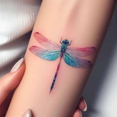 a colorful dragonfly tattoo on the wrist