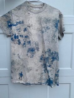 a t - shirt hanging on a door with blue and white paint all over it