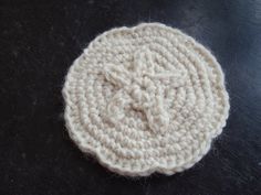 a white crocheted object sitting on top of a black table next to a pair of scissors