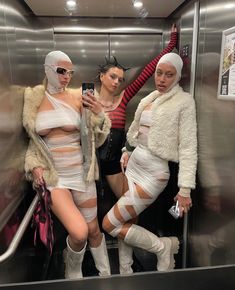 three women dressed in costumes standing on an escalator and taking a selfie