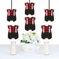 a table topped with vases filled with white flowers and baby onesuits hanging from clothes pins