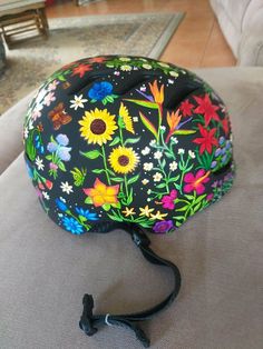 a helmet with flowers painted on it sitting on a couch next to a black cord