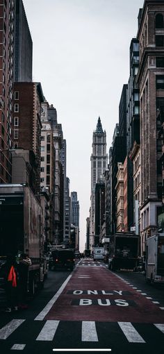 an empty city street with tall buildings and people walking on the sidewalk in the distance