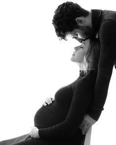 a pregnant woman leaning on the back of a man