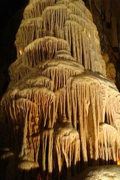 a very tall structure with lots of icicles hanging from it's sides in a cave