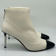 These Ivory White Lambskin Leather Booties Feature A Pointed Black Patent Calfskin Cap Toe. Faux Pearl Silvertone Metal Cc Embossed Detail On The 3.5" Patent Leather Heel. Back Zip. Padded Leather Insole And Leather Sole. Made In Italy. Designer Color: Black. Size: 40.5 Eu (Insole Measures 10.5", Heel: 3.5"). Typically Chanel Shoes Run Small. Brand New With The Box. Elegant White Heeled Boots With Sculpted Heel, Cream High Heeled Boots With Reinforced Heel, Cream Leather Heels For Winter, Chic Cream High Heel Boots, Chic White Heeled Boots With Padded Heel, Chic Cream Heeled Boots, Chic Cream High Heeled Boots, Elegant White Heeled Boots With Padded Heel, Luxury White Heeled Boots For Formal Occasions