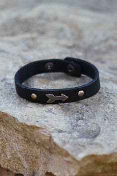 This thin leather bracelet cuff is ornamented with a clean little arrow. A great mini touch of adventure and a cute accent to pair with your other arm candy. -Color: Black -Handmade -Genuine Leather -Measurements: 8"L -Closure: Snap -Imported Arrow Bracelet, Leather Ideas, Leather Cuffs Bracelet, Bracelet Cuff, Arm Candy, Leather Jewelry, Modern Fashion, Cuff Bracelets, Leather Bracelet