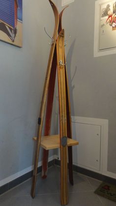 three wooden skis leaning against the wall in a room with paintings on the walls