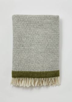 a gray and green blanket with fringes on it's edge, against a white background