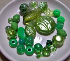 a white plate topped with lots of green glass beads