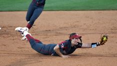 a baseball player sliding into home plate to catch a ball while another catches the ball