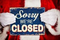 santa claus holding up a sign that says sorry we're closed