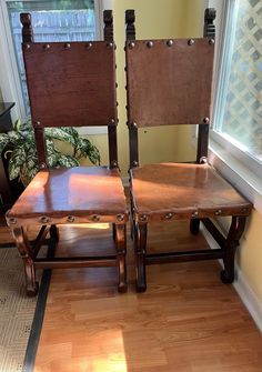 two wooden chairs sitting next to each other on a hard wood floor in front of a window