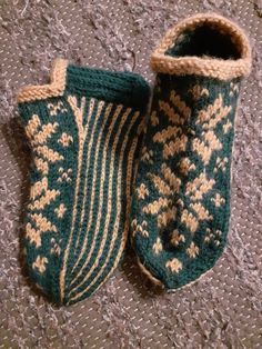 two green and white knitted slippers sitting on top of a carpeted floor