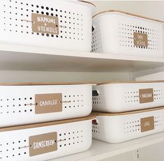 some white bins with brown labels on them are sitting on shelves in a closet