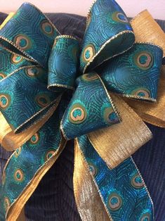 a blue and gold bow with peacock feathers on it's side, sitting on top of a sweater