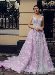 a woman is standing in front of a building wearing a pink and white wedding dress