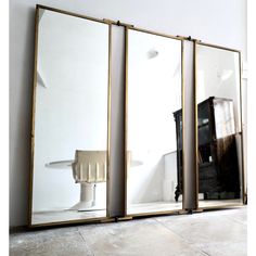 three mirrors sitting next to each other in front of a white wall on the floor