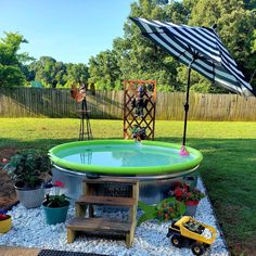 an inflatable pool surrounded by gravel and plants with a black and white striped umbrella