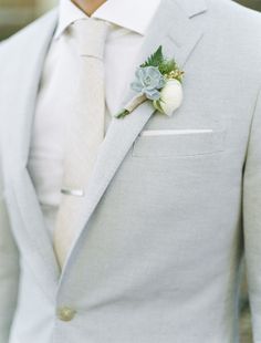 a man in a gray suit with a boutonniere on his lapel