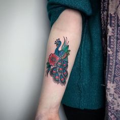 a woman's arm with a peacock and flowers tattoo on the left side of her arm