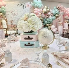 a table topped with lots of white and pink flowers on top of a table covered in balloons