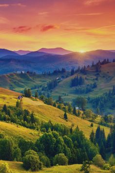 the sun is setting over mountains with trees and grass in the foreground, as seen from above