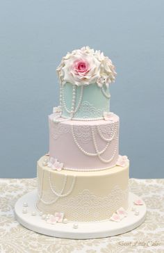 there is a three layer cake with flowers on the top and pearls on the bottom