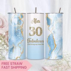 three blue and white canisters with gold foil lettering on them, one has a pink rose in the background