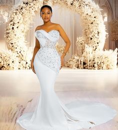 a woman in a white dress standing next to a floral arch with flowers on it