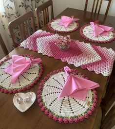 the table is set with pink napkins and placemats on doily that are crocheted