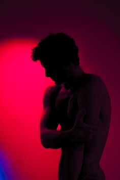 a man standing in front of a red and blue light with his hands on his chest