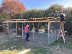 two people standing on top of a chicken coop