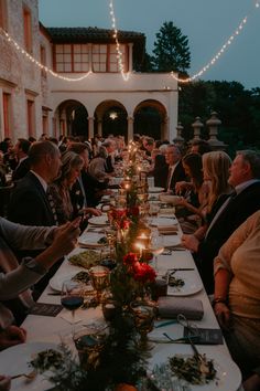 a group of people sitting at a long table with food and drinks in front of them