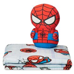 a spiderman stuffed animal sitting on top of a bed next to a pillow and blanket