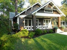 a brown house with white trim on the front porch and covered in grass, surrounded by trees