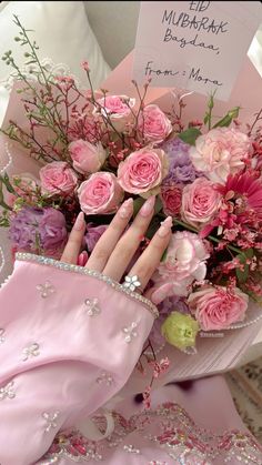 a woman's hand holding a bouquet of pink roses