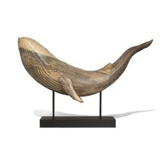 a wooden sculpture of a whale on a black stand