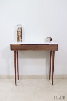 a table with a vase on top of it next to a white wall and floor