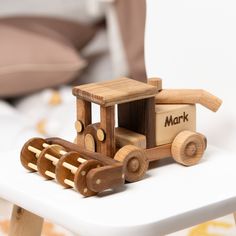 a wooden toy tractor with the word mark on it sitting on a small white table