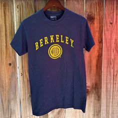 Brand New, Never Worn With Tags, Uc Berkeley Official Seal T-Shirt. Navy And Gold. Show Your Golden Bear Pride By Wearing This Classic Uc Berkeley T-Shirt. Casual Short Sleeve T-shirt With University Logo, Casual Cotton T-shirt With University Logo, Blue School Spirit T-shirt With Text Print, University Logo Graphic Tee With Crew Neck, Blue College Shirt With Screen Print, Blue Screen Print Shirt For College, Sporty Crew Neck T-shirt With University Logo, Navy Casual T-shirt With Screen Print, Casual Navy T-shirt With Screen Print