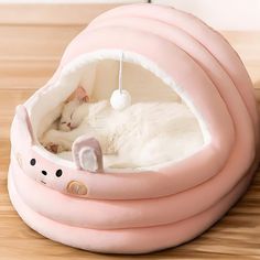 a white cat sleeping in a pink kitty bed