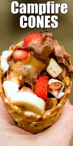 a hand holding a waffle filled with fruit and ice cream