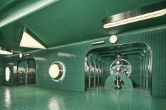 an empty green tiled bathroom with mirrors and lights