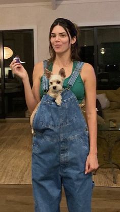 a woman in overalls holding a small dog