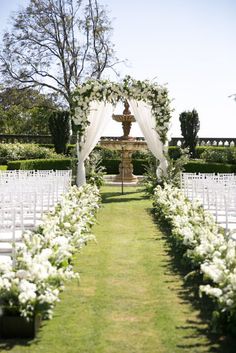 an outdoor ceremony setup with white flowers and greenery