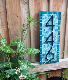 a wooden sign that is on top of a shelf next to some plants and flowers