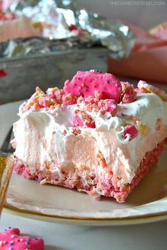 a piece of cake on a plate with sprinkles and pink frosting